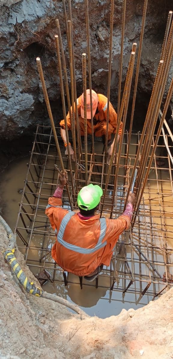 Worker tying reinforcement in a footing pit