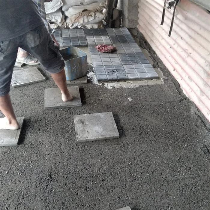 Floor tiles being laid on a prepared bed